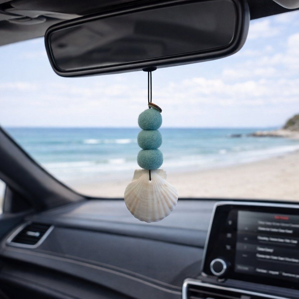Teal coastal felt ball car diffuser with seashell hanging in vehicle